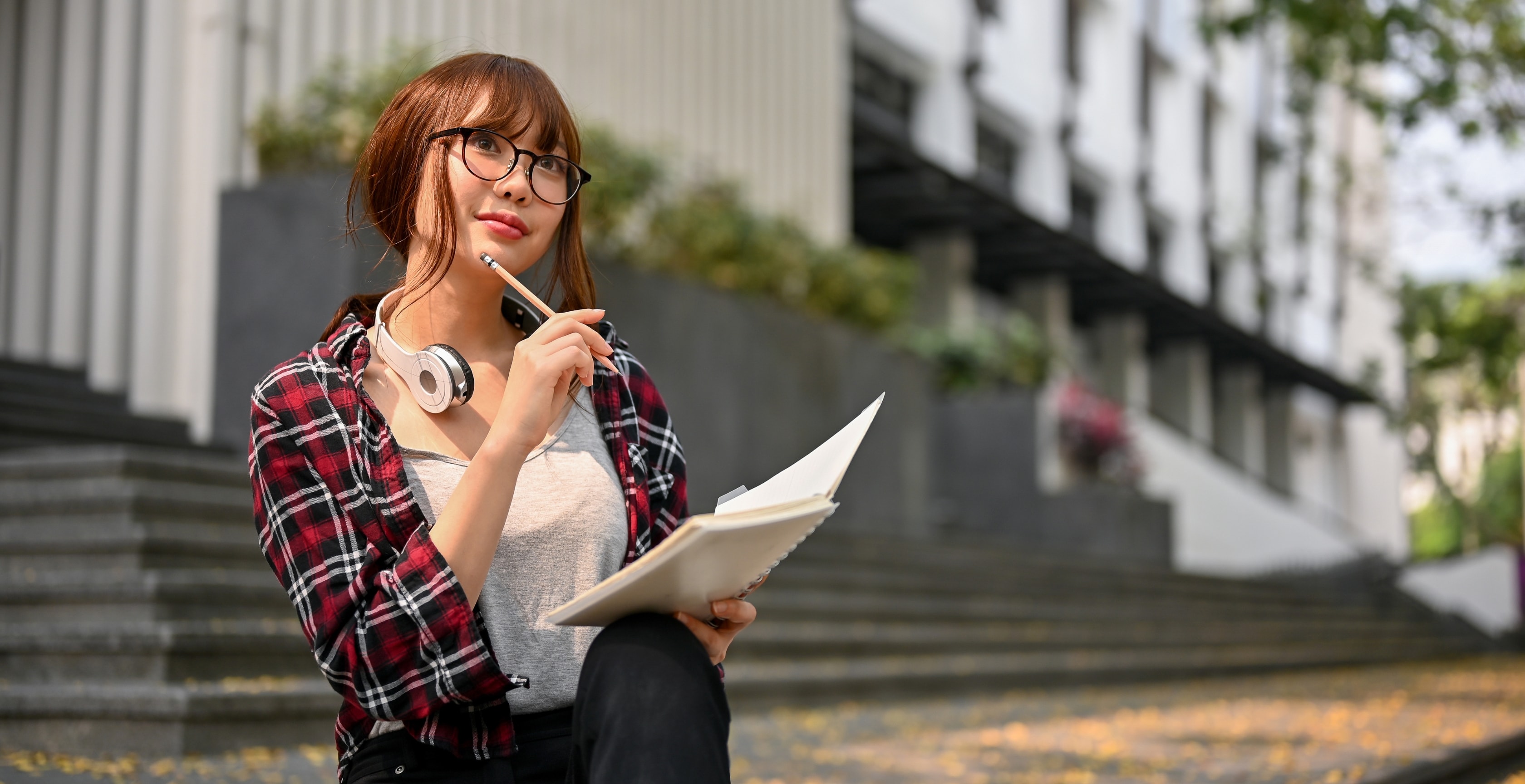 A thoughtful content creator taking notes outside, considering 'Do you have to pay taxes on OnlyFans?' while planning financials.