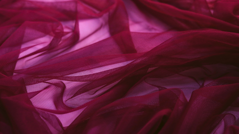 A close-up of a burgundy colored sheer fabric