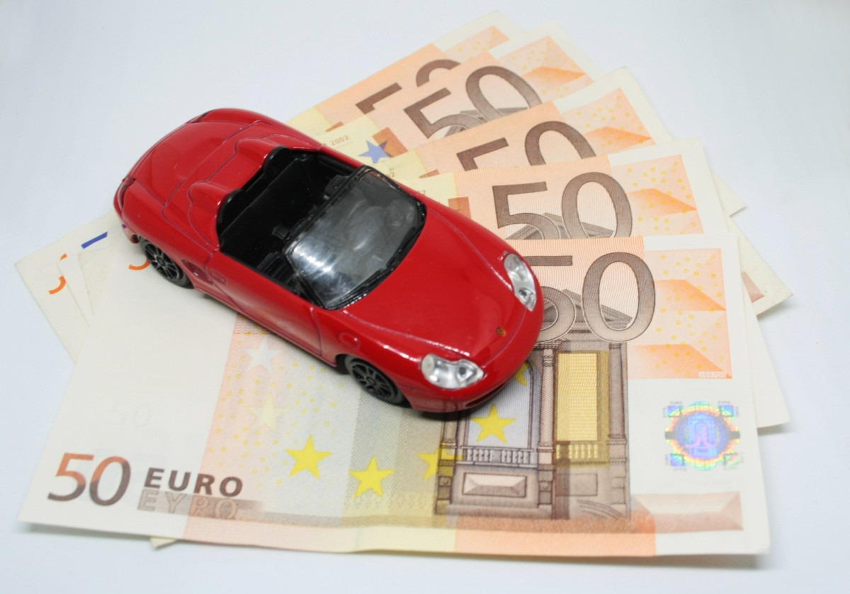 Red car toy with a bunch of 50 euros under it