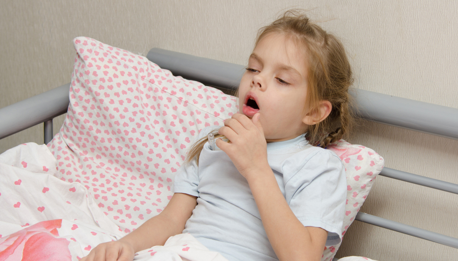 Syk jente hoster i seng med termometer.