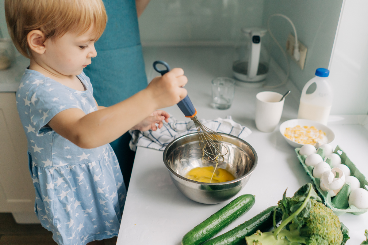 little girl helping scramble eggs