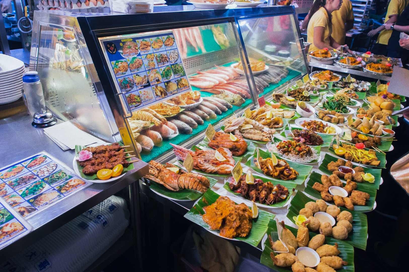 Seafood display counter featuring fresh fish, prawns, and cooked dishes.