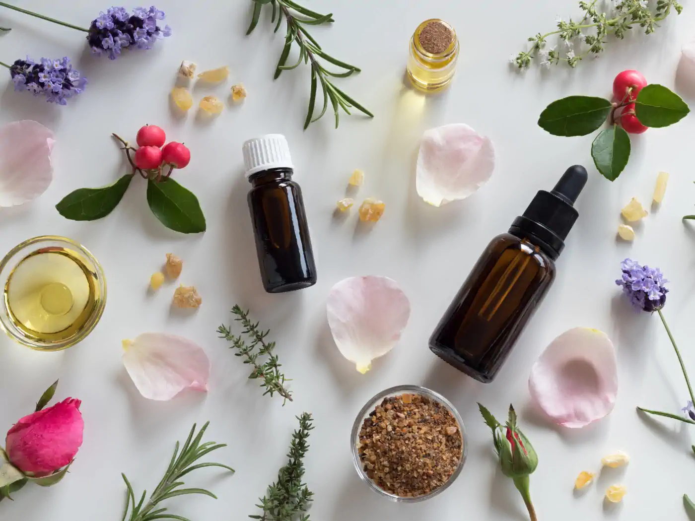 Various essential oil bottles surrounded by flowers and herbs on a white background. Collection: Essential Oils, Fabulous Flowers & Gifts.