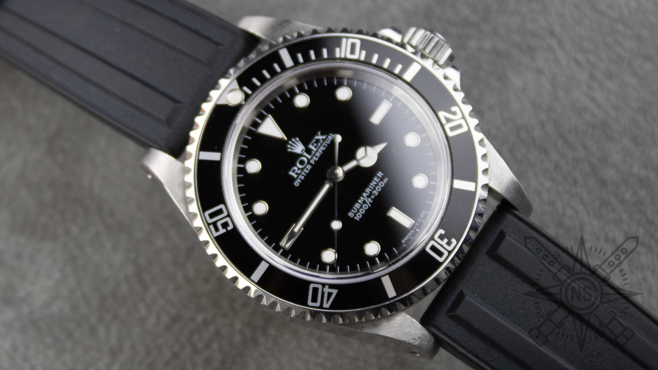 A close-up of a Rolex Submariner watch with a rubber strap, showcasing its sleek design.