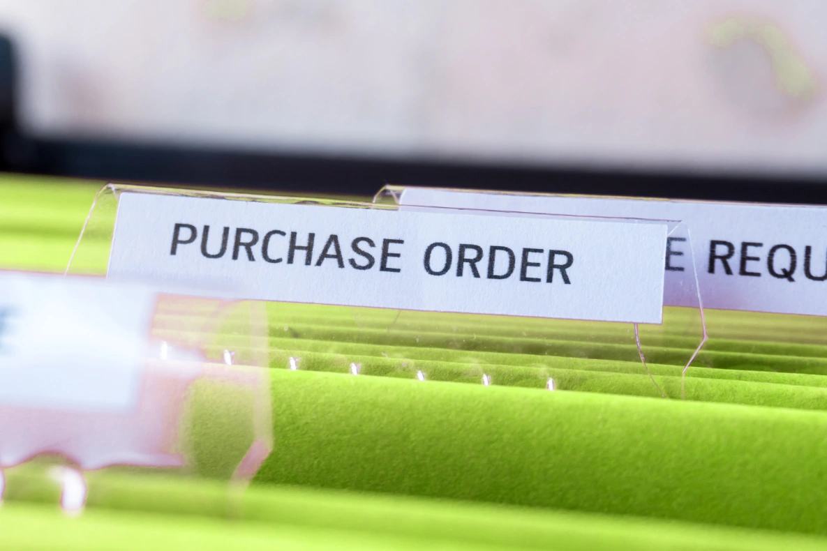A close-up view of a file folder labeled "PURCHASE ORDER" in a filing cabinet.
