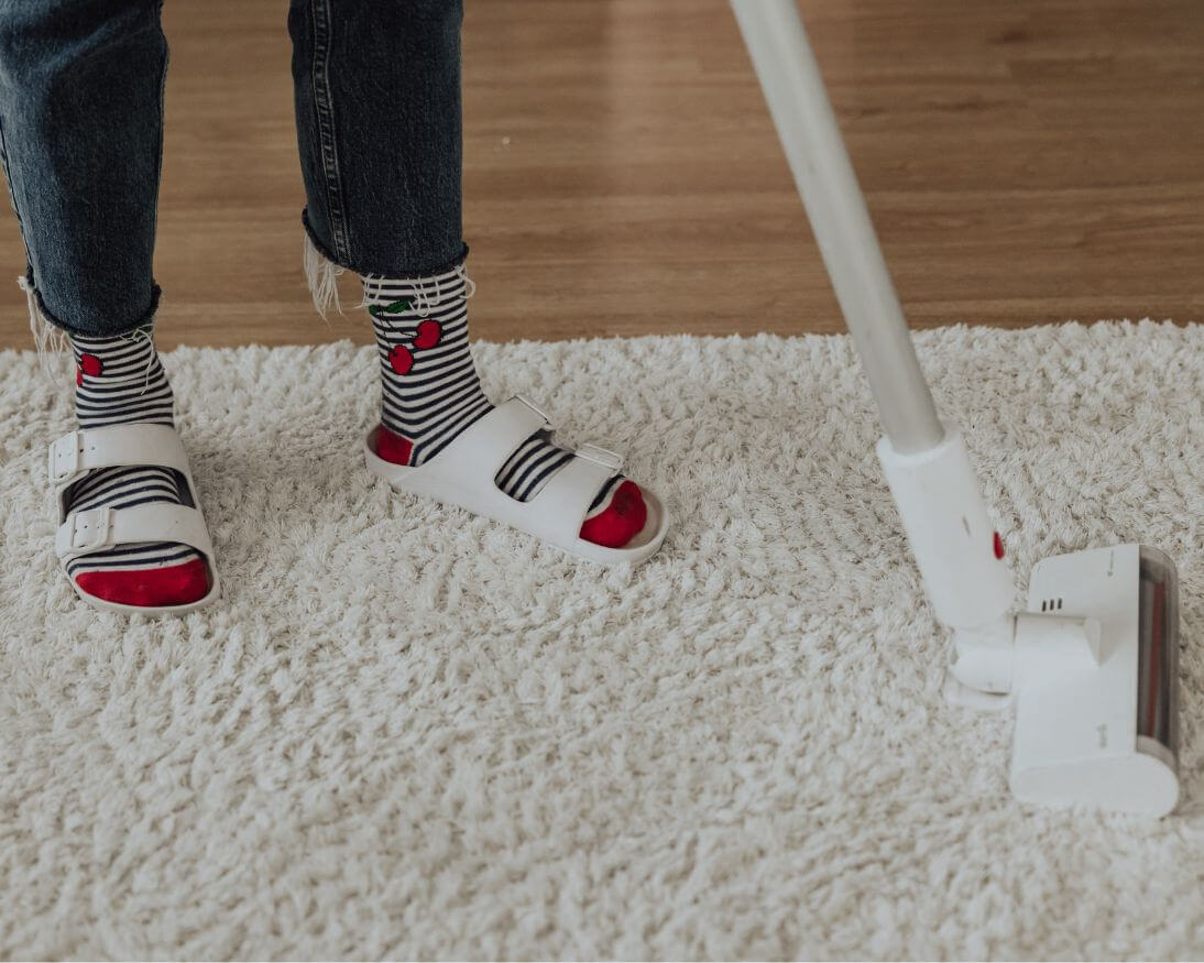 A person using a vacuum cleaner to remove pet odors from a carpet