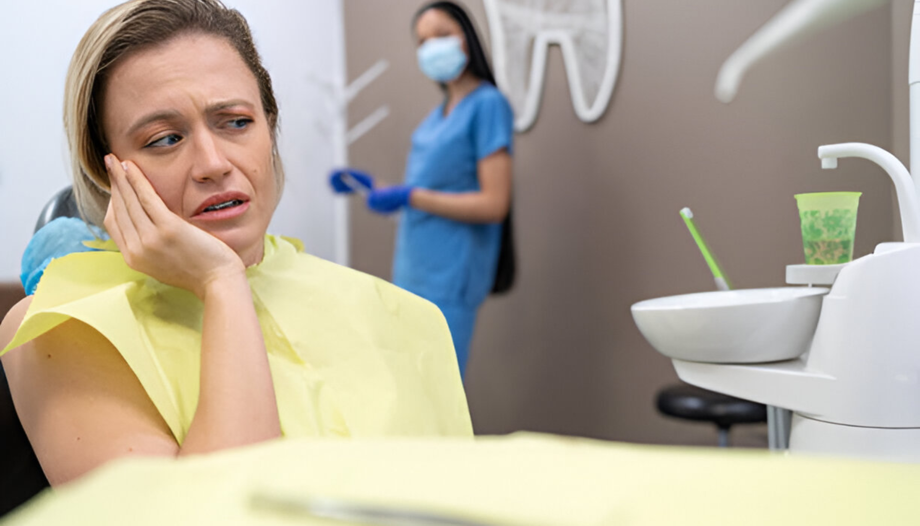 Hvilke diagnoser gir rett til gratis tannlege 9 Kvinne i tannlegestol holder kinnet i smerte, ser bekymret ut mens tannlege forbereder behandling i bakgrunnen