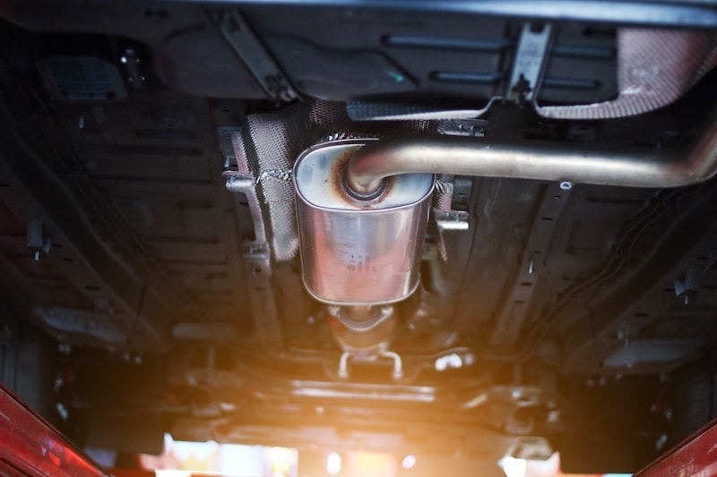 Close-up view of a catalytic converter under a vehicle at AutoFair Toyota of Tewksbury, Massachusetts. Ensure optimal emissions control and exhaust system performance with expert maintenance and service.
