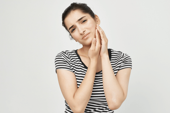 female holding her jaw from TMJ pain in need of tmj treatment calgary