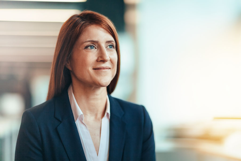 red-haired woman with blazer smiles and looks up during a job interview