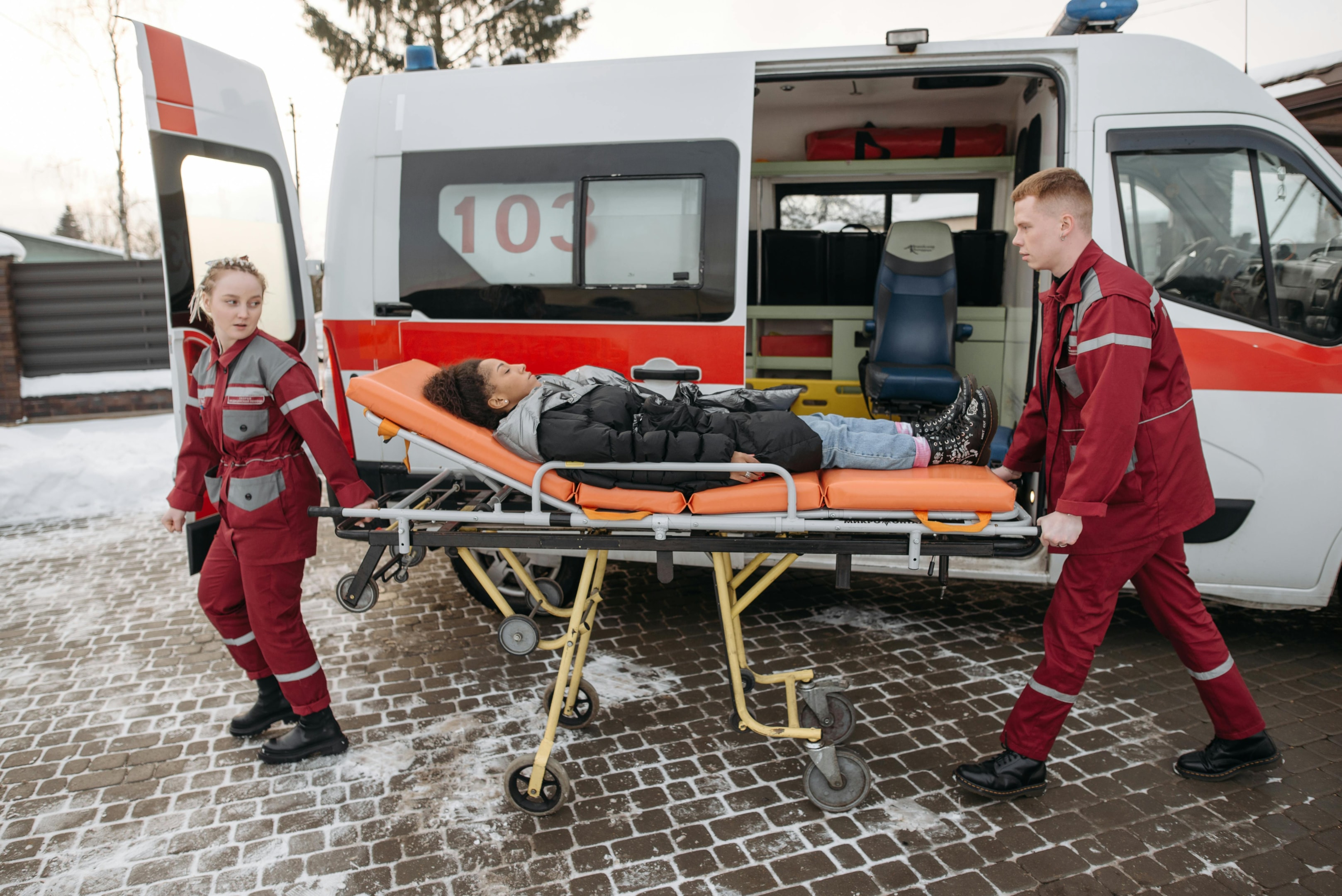 EMS professionals carrying an injured woman on a stretcher.