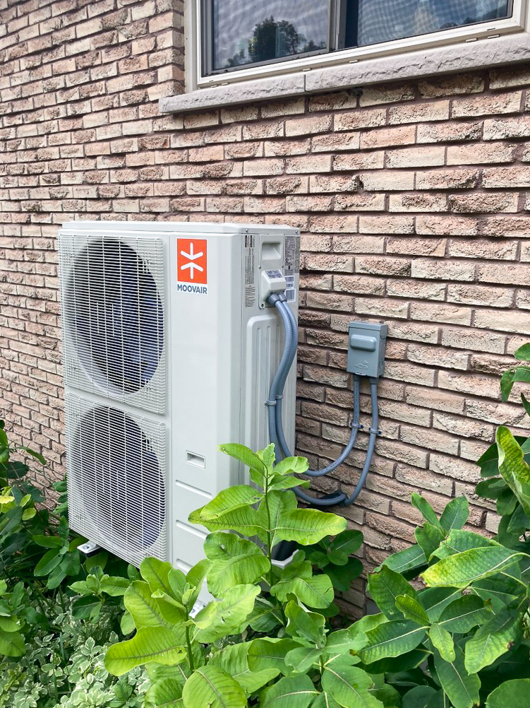 A Moovair heat pump located on the side of a home. 