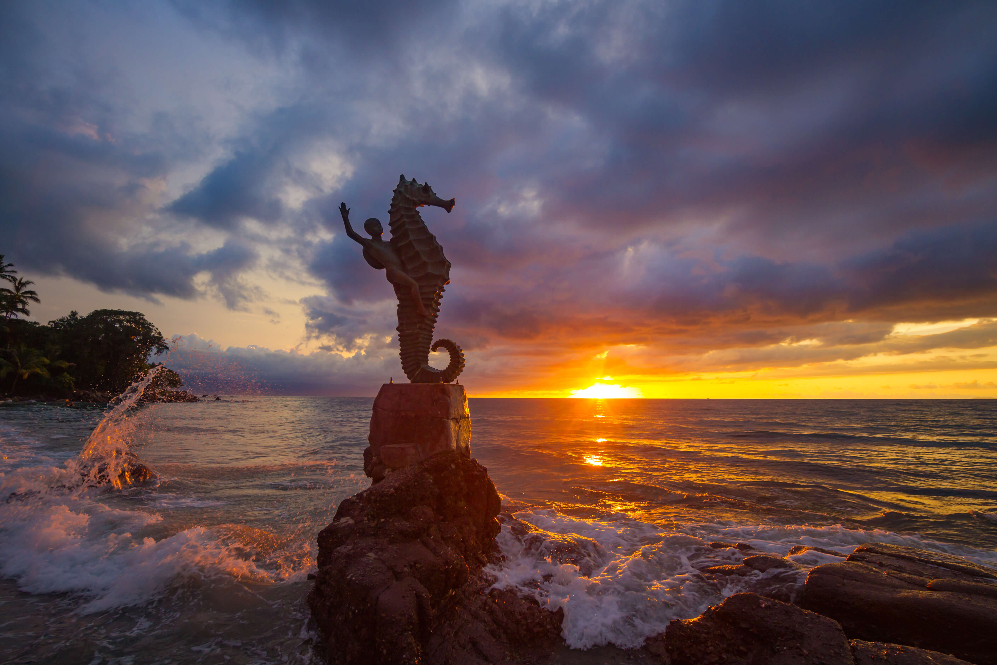 Sunset with a seahorse statue on a rock