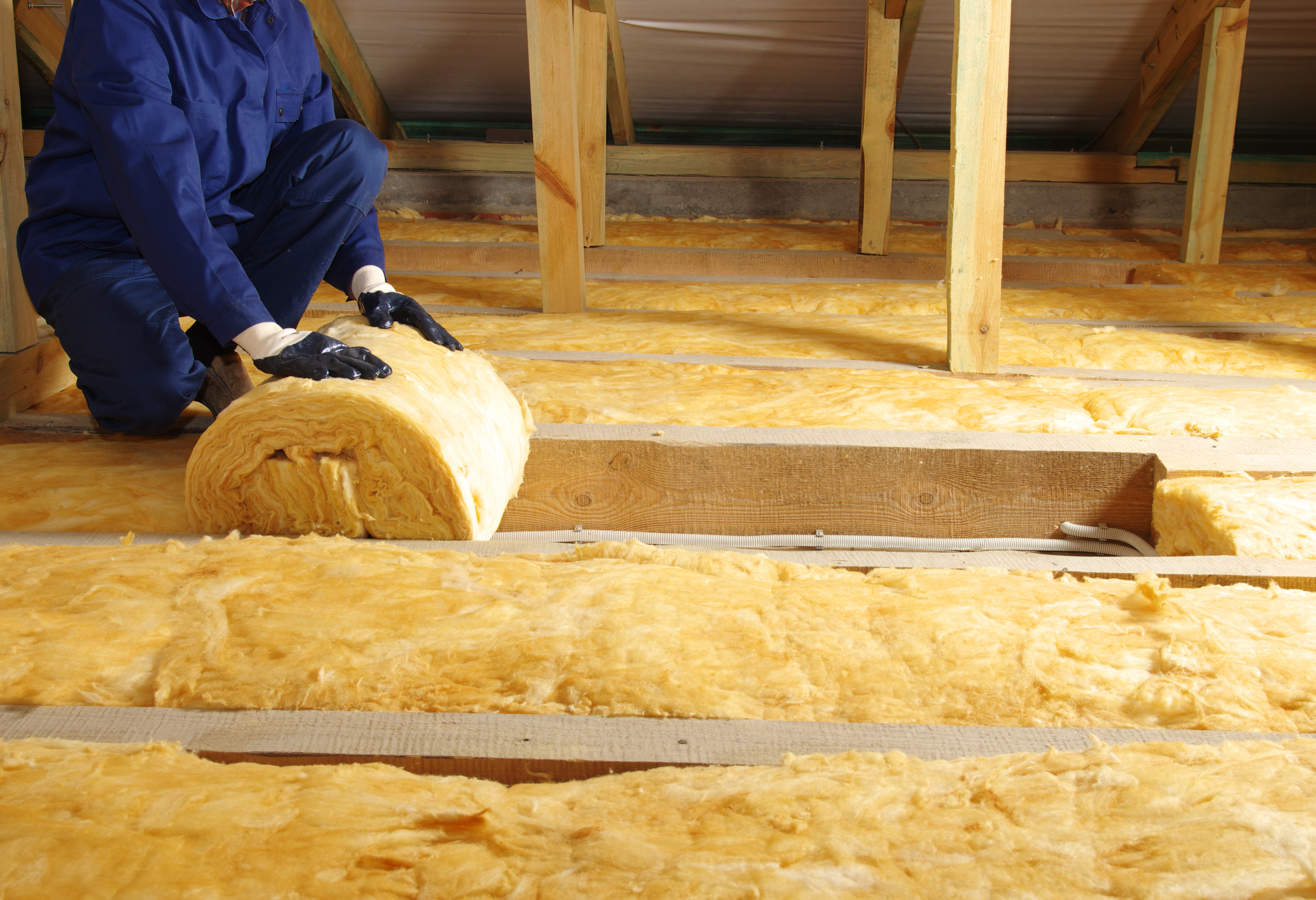 A person installing insulation in a home, improving energy efficiency