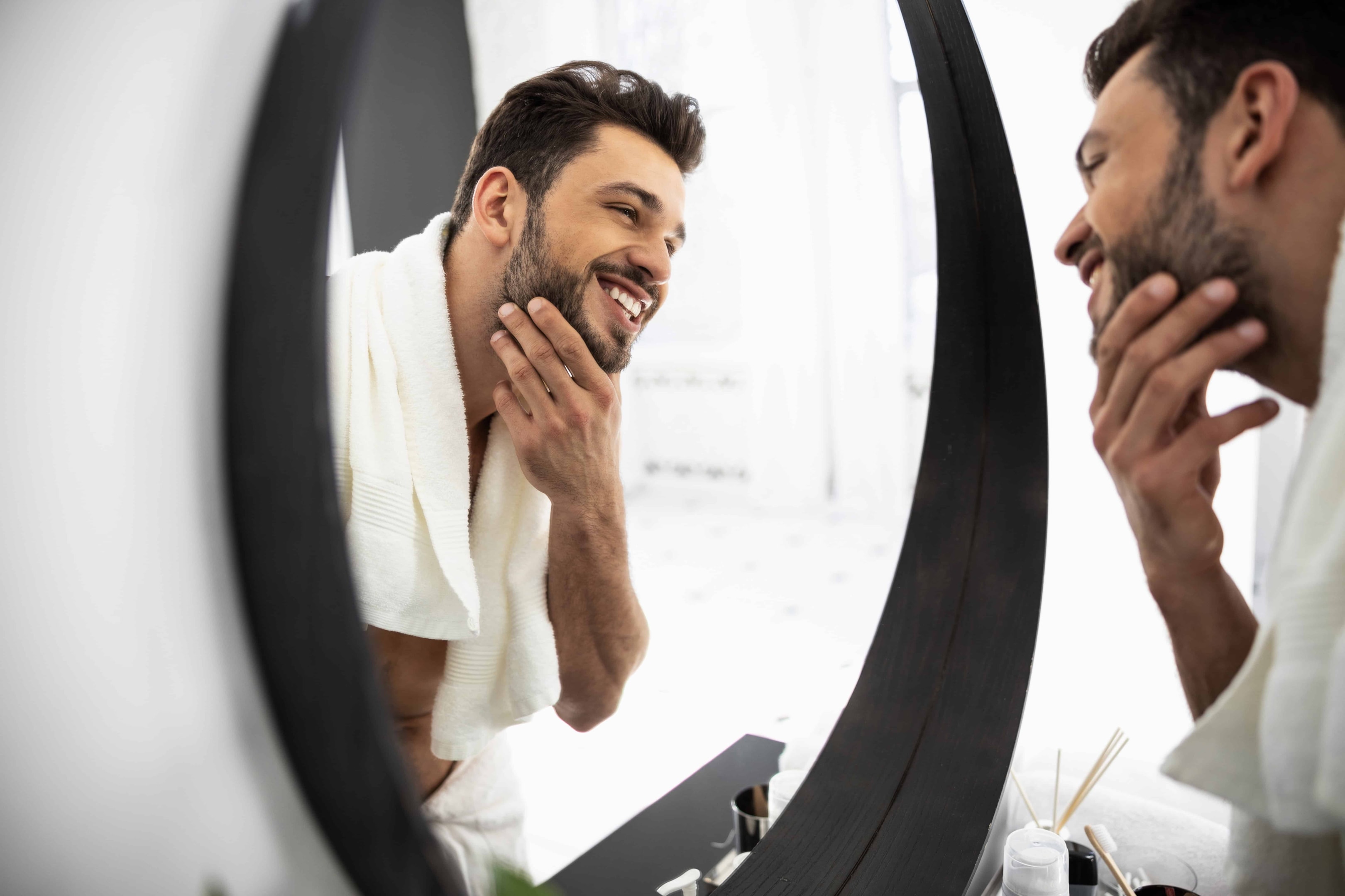 A man looking in the mirror and smiling at himself. He wants to feel confident and have a happy life.