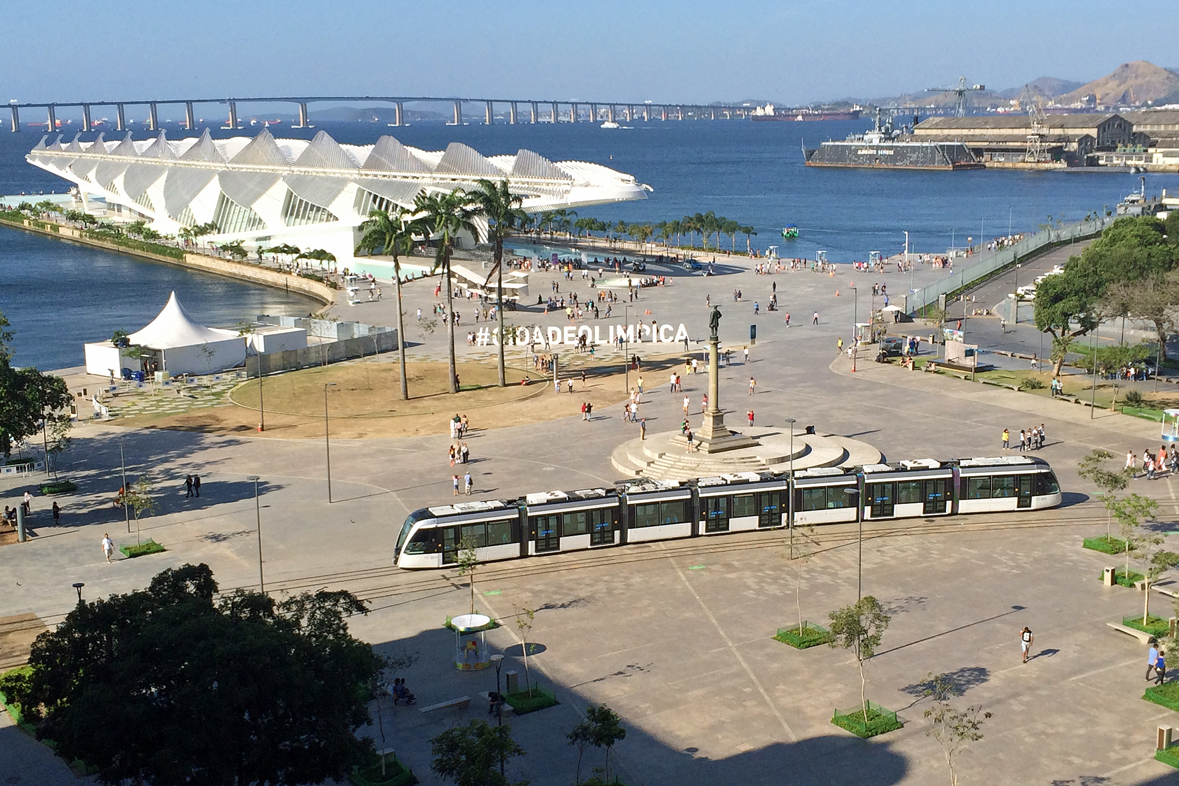 Vista da Praça Mauá com o trem passando e a Baía de fundo. Imagem: Creative Commons.