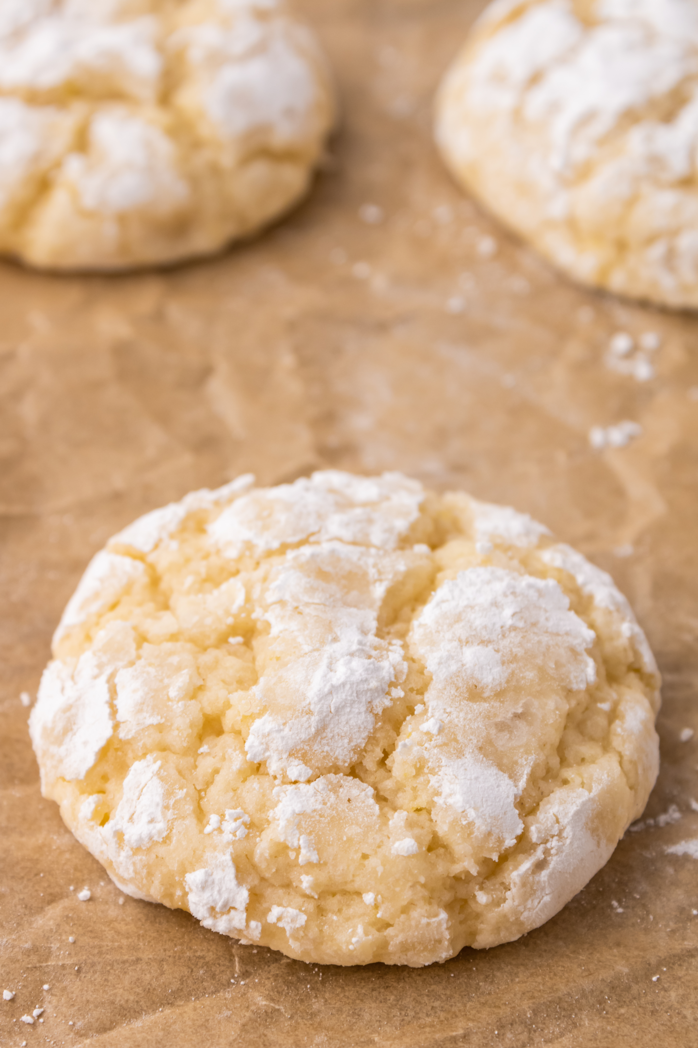 lemon crinkle cookie rolled in icing sugar on parchment paper