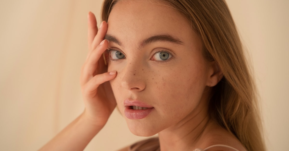 Close-up of a woman contemplating tax compliance, with a hand on her face and a thoughtful look.