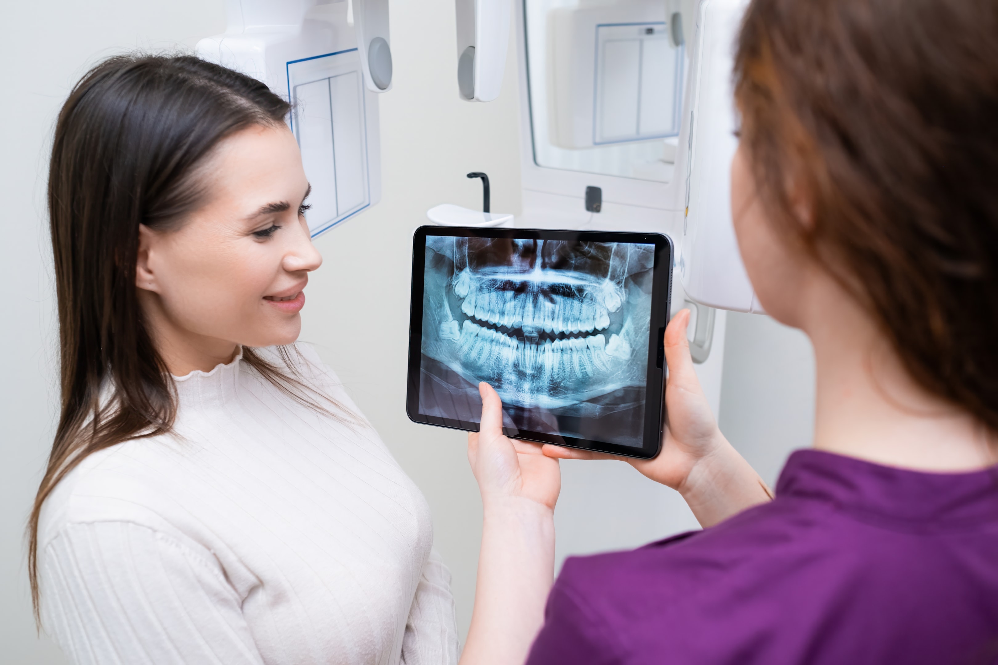 an oral surgeon showing a patient an x-ray of their teeth to better explain a dental implant