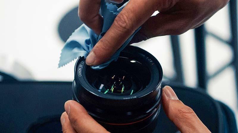 Man cleaning camera lens with a soft microfiber cloths