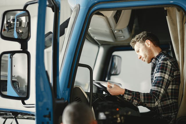 A driver inside a truck, looking over a roadside inspection report. 