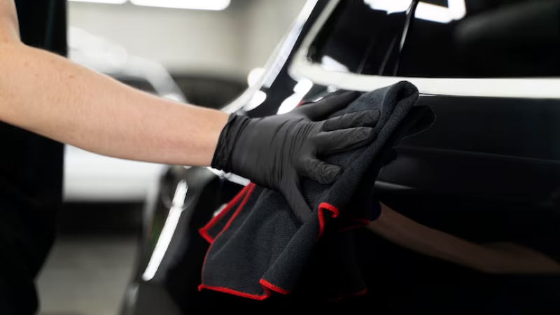A PPF installer using microfiber towel to clean after PPF