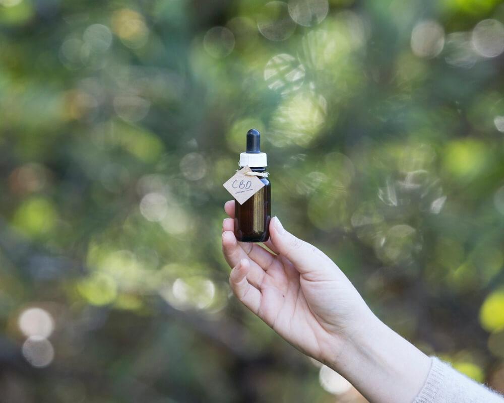 a person holding a CBD oil bottle