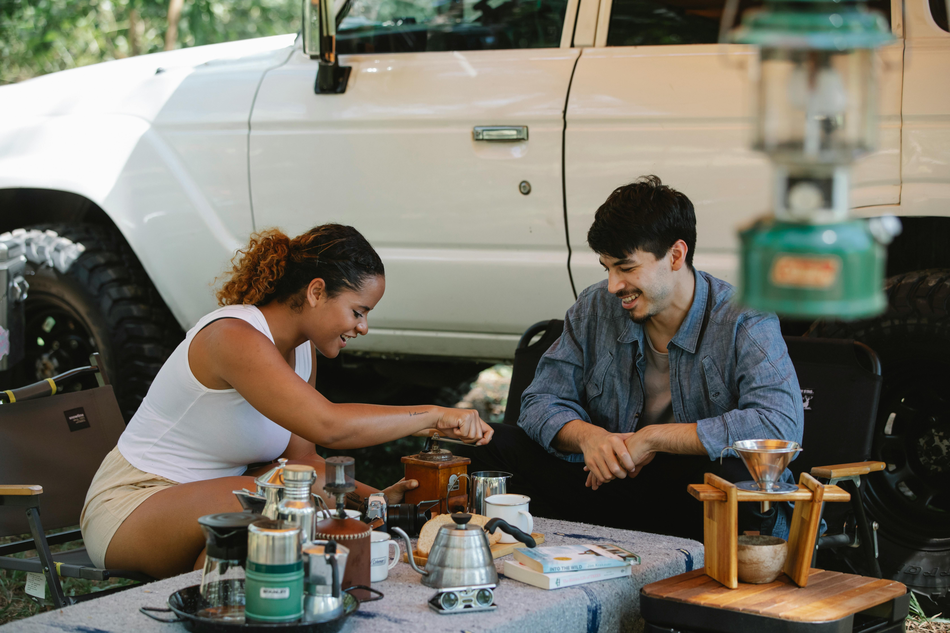 smiling couple grinding coffee outdoors