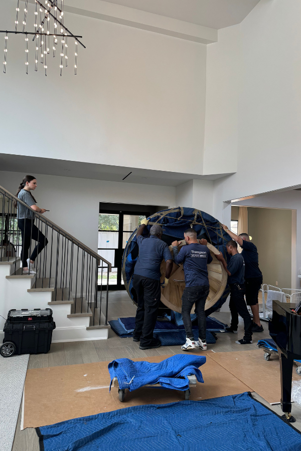interior designers and workers installing a table in an open-concept interior, which is also part of the procurement process