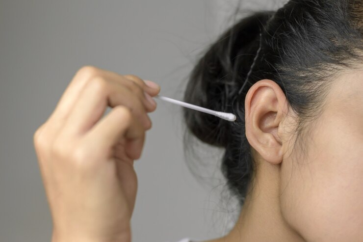 Woman cleaning ear using a cotton swab