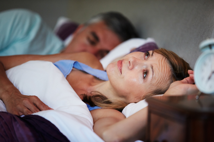 An image of a woman in bed wide awake because of her husband's snoring. 