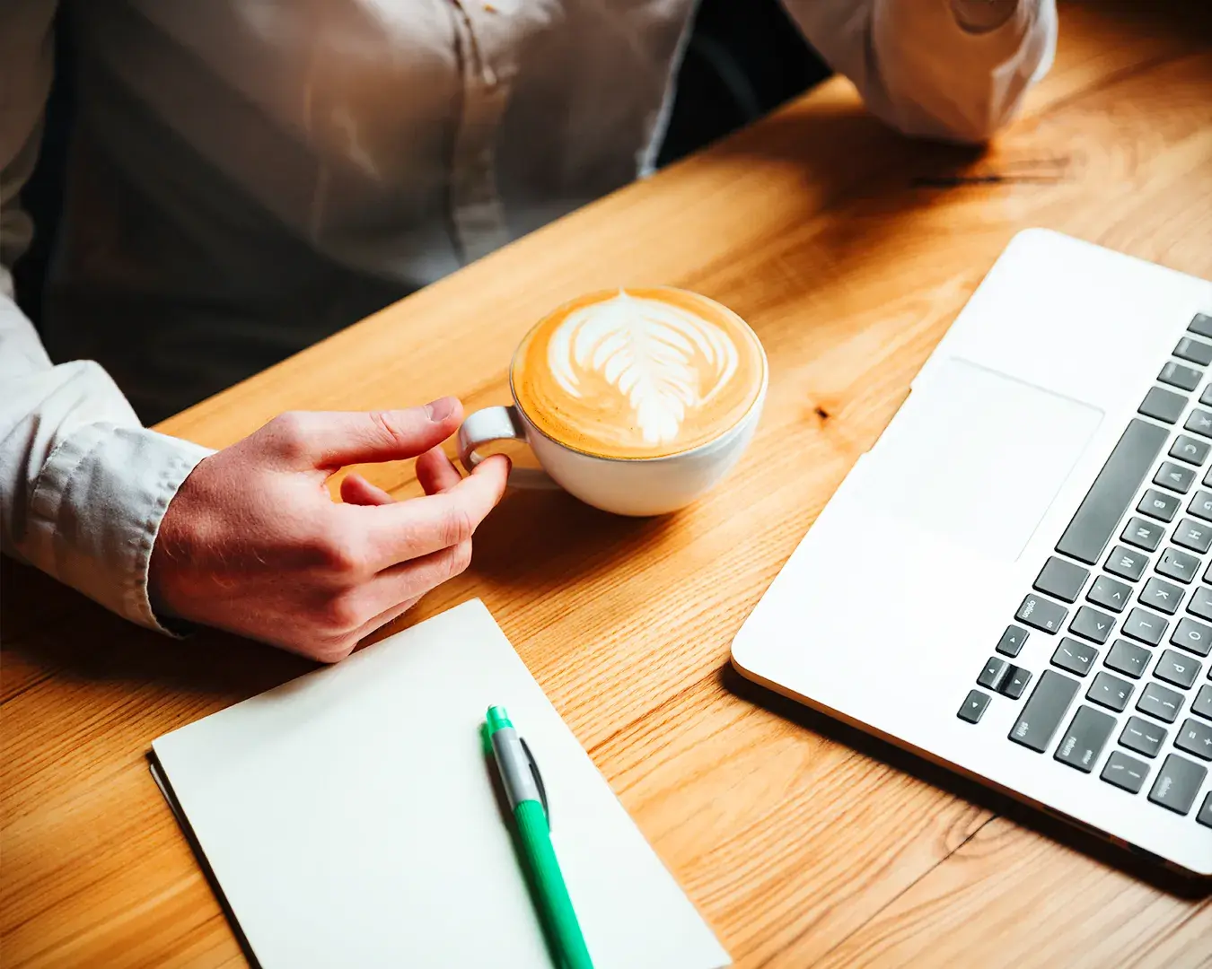 Restaurant owner reviewing marketing plans beside laptop, notebook, and coffee in warm workspace environment, representing food delivery marketing analysis and customer retention strategy.