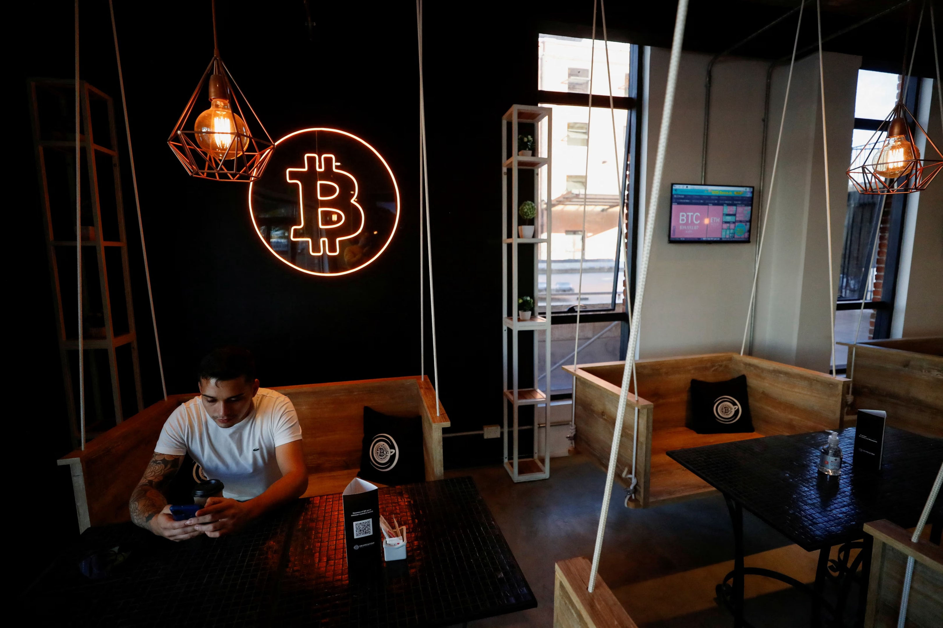 Future outlook for cryptocurrency in Argentina depicted by man sitting in Bitcoin cafe. 