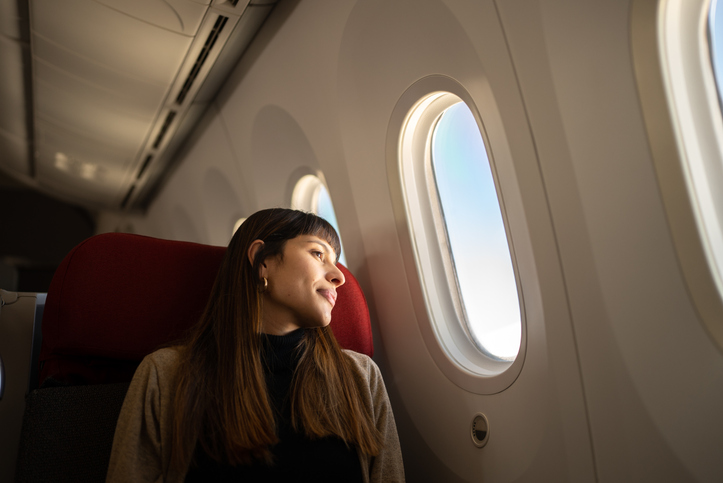 Young woman looking out the window of an airplane.