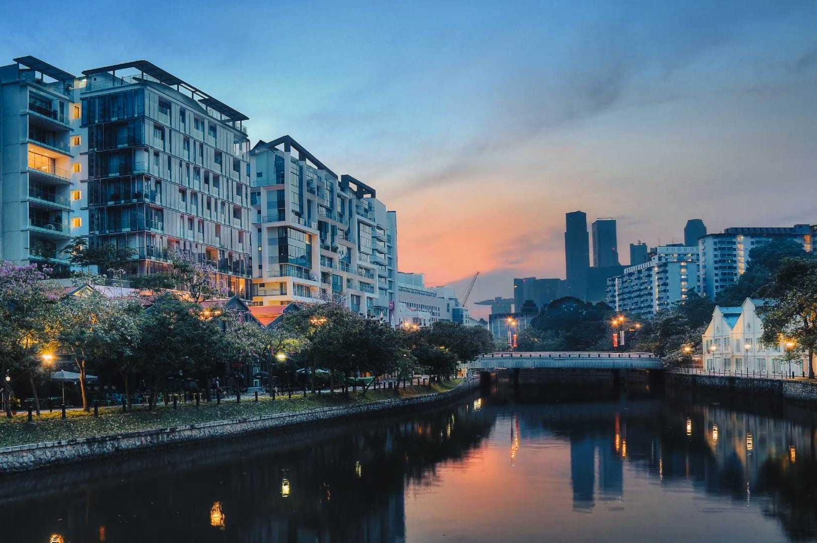 Riverfront lined with residential buildings and city lights reflecting over the Singapore River.