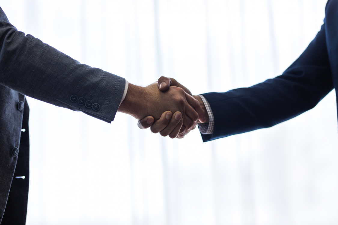 Two business professionals shaking hands after closing a broker deal