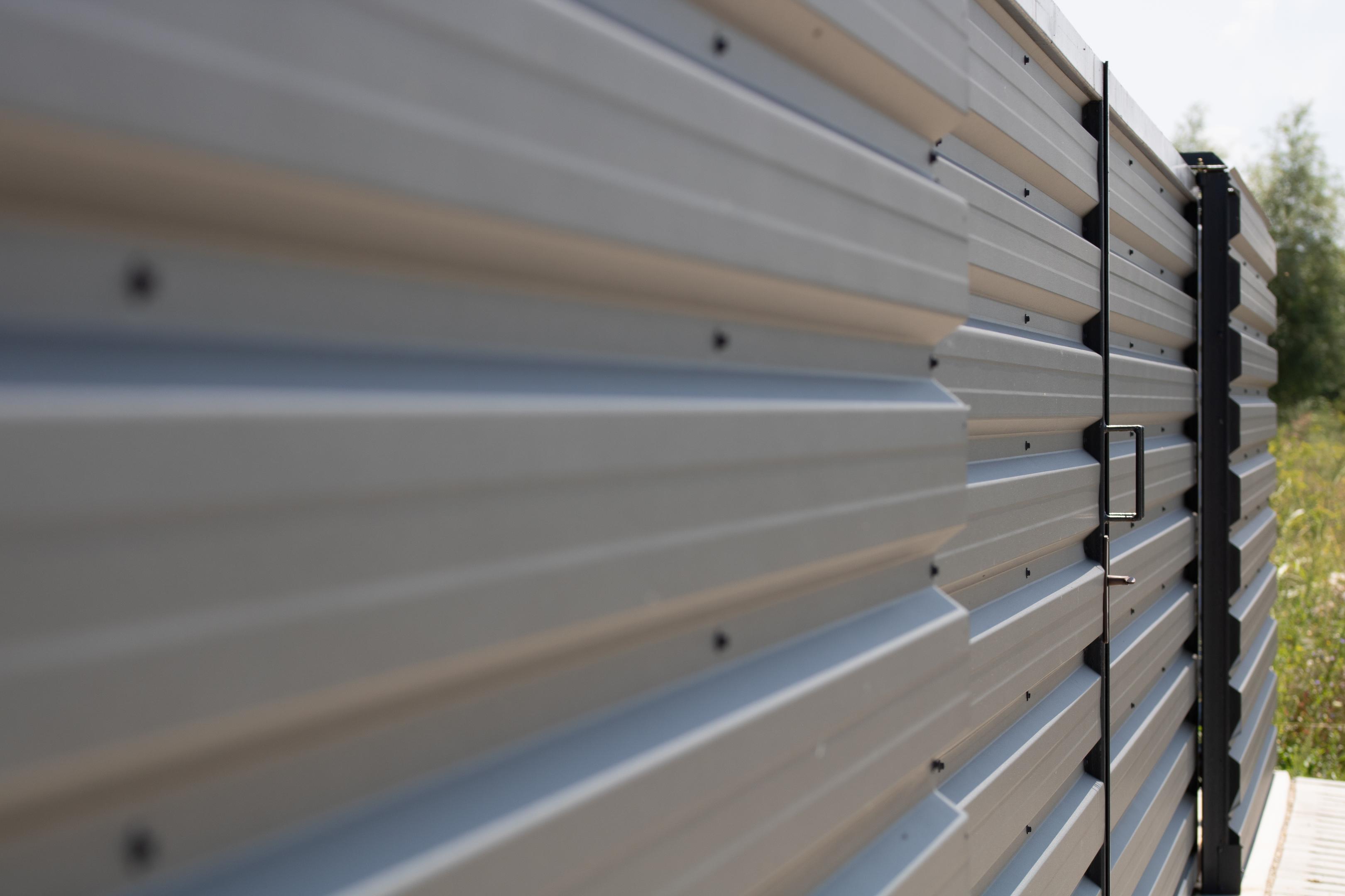 Grey Metal Privacy Fence Along a Grassy Field
