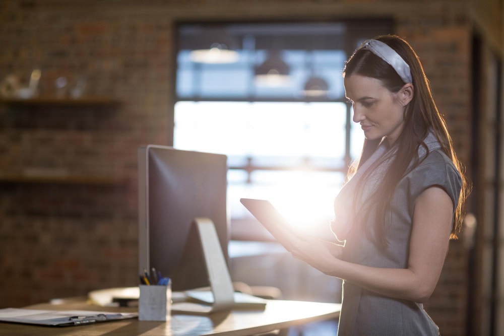 Businesswoman using tablet in office to manage her entire phone system and business apps.