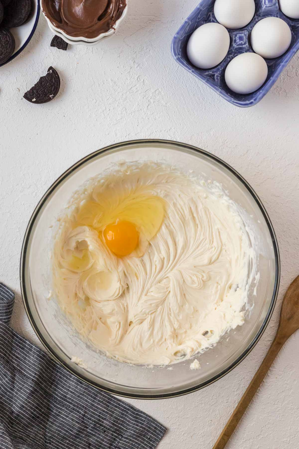 egg added to cheesecake batter in bowl