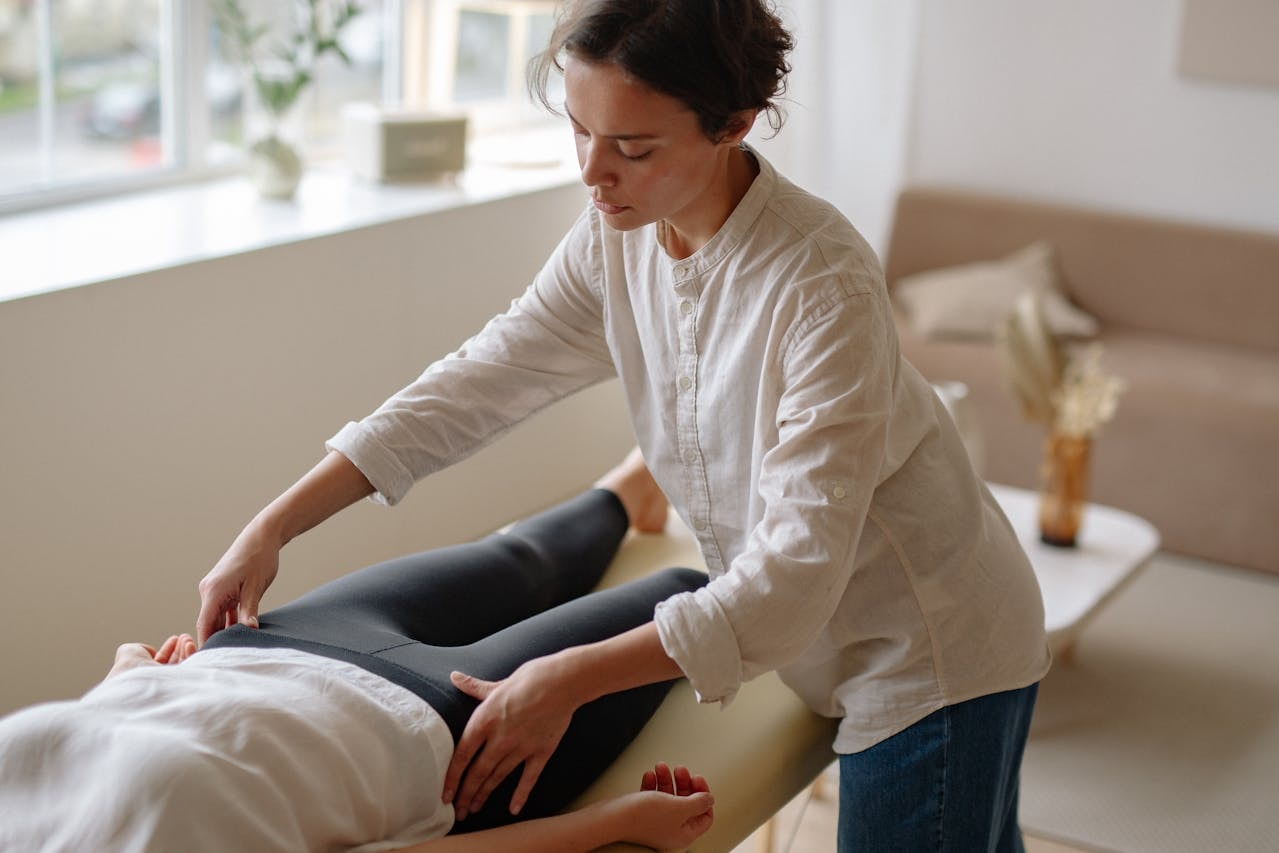 Physical therapist assessing a patient’s hip range of motion on a treatment table, supporting rehab planning and hip flexor strain recovery time expectations.