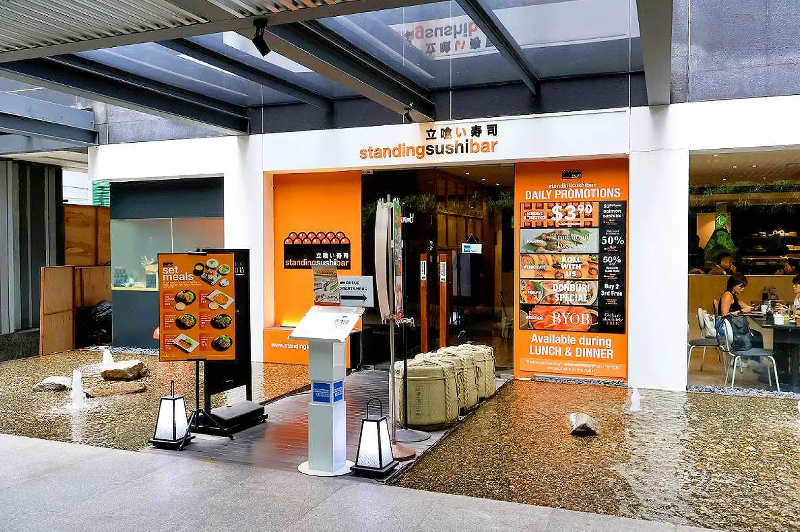 Standing Sushi Bar Singapore restaurant entrance with orange Japanese sushi bar branding