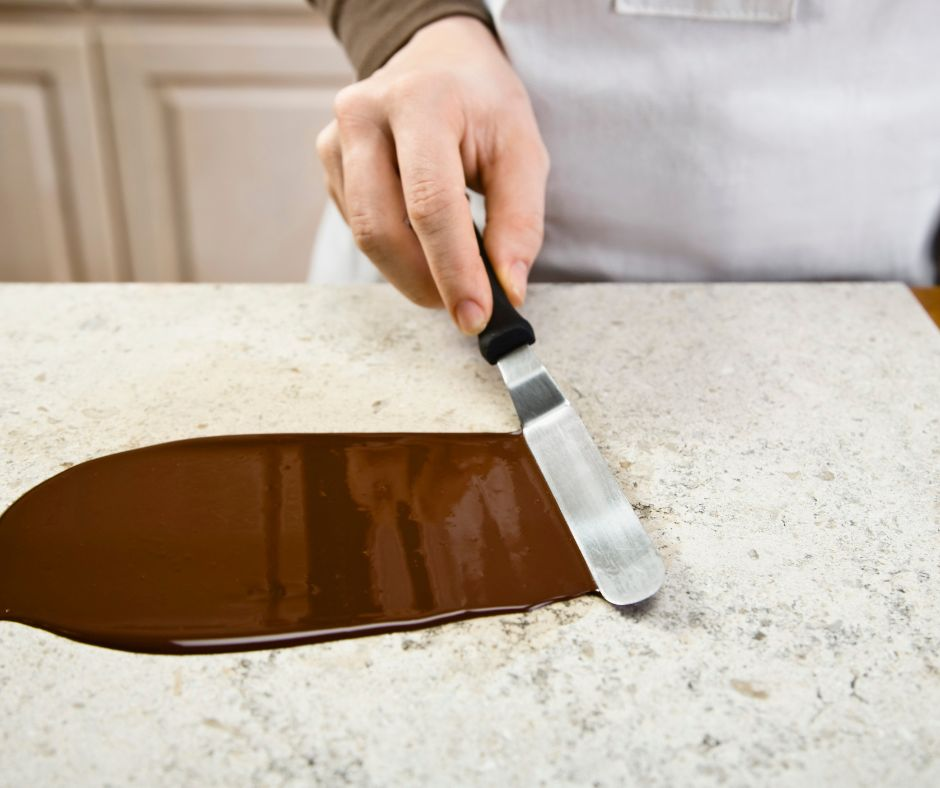 chocolate being tempered on a marble slab with a spatula