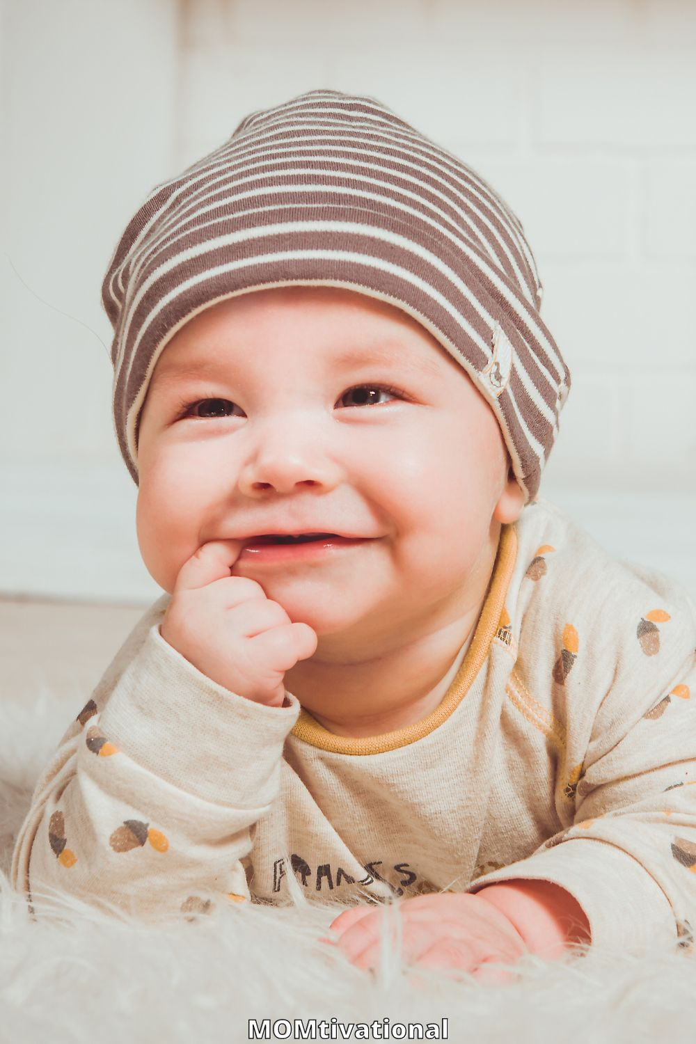 Baby boy smiling with hand sin his mouth