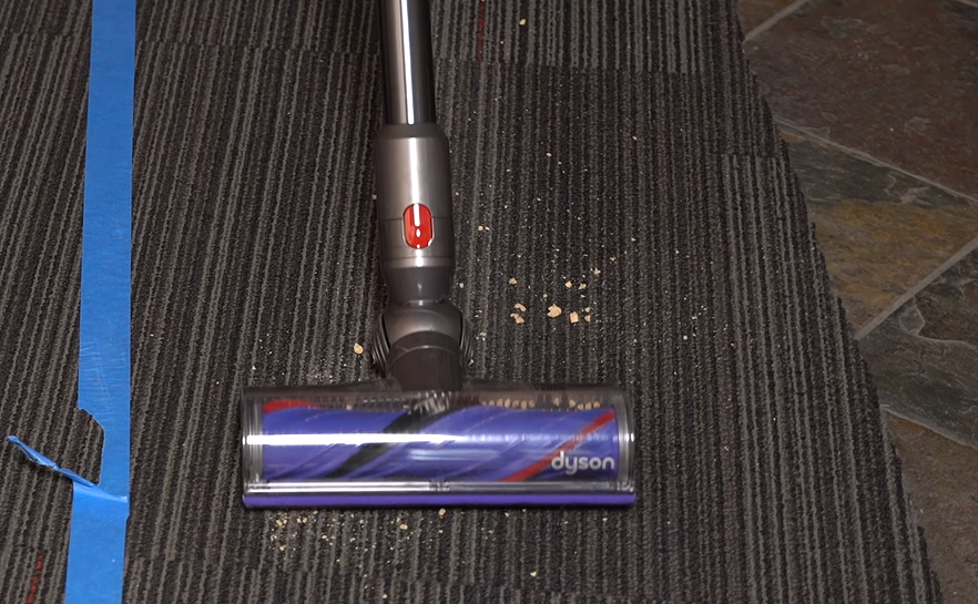 Dyson V8 cordless vacuum picking up cereals on carpet