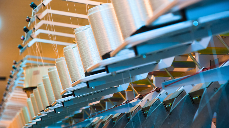 Close-up of a textile machine with bobbins of thread.