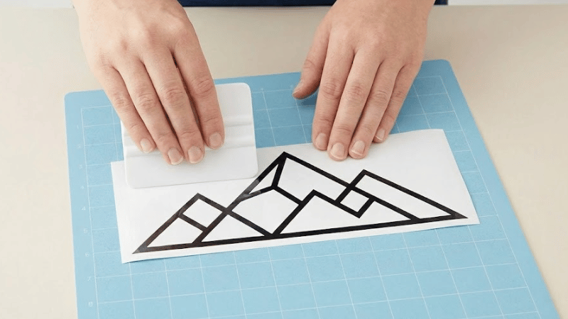 A man is applying transfer tape to the vinyl decal.