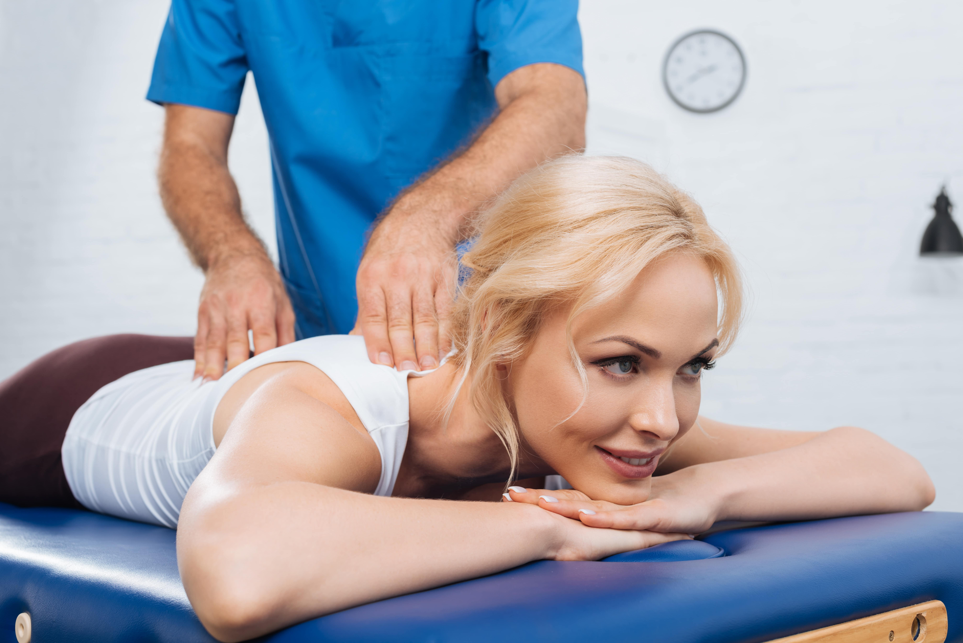 Woman receiving treatment for her lower back muscles from a doctor. Massage and chiropractic provide effective care.