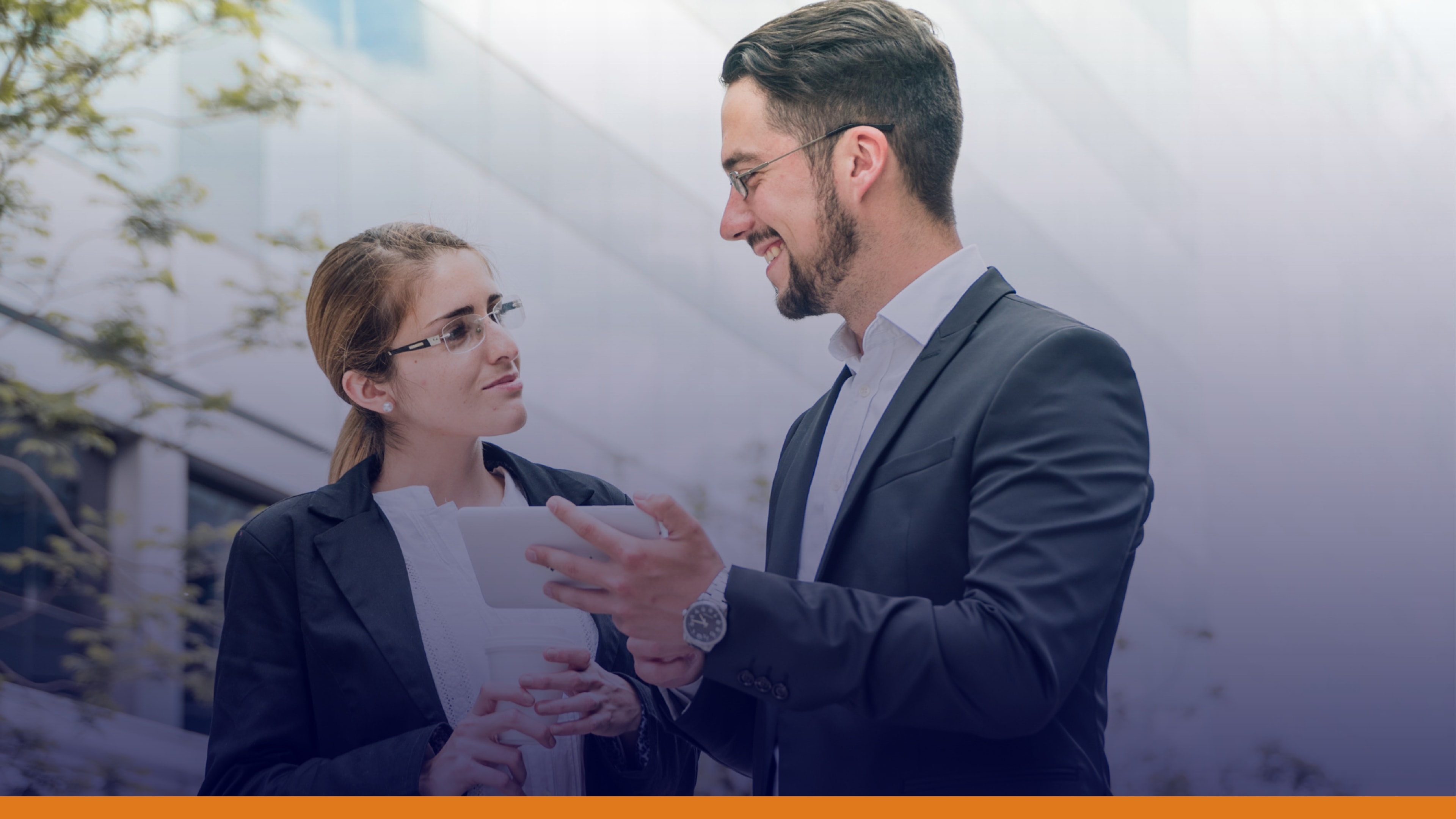 Two professionals talking outside an office building while reviewing a tablet, symbolizing collaboration with local authorities and dependable emergency notification systems.