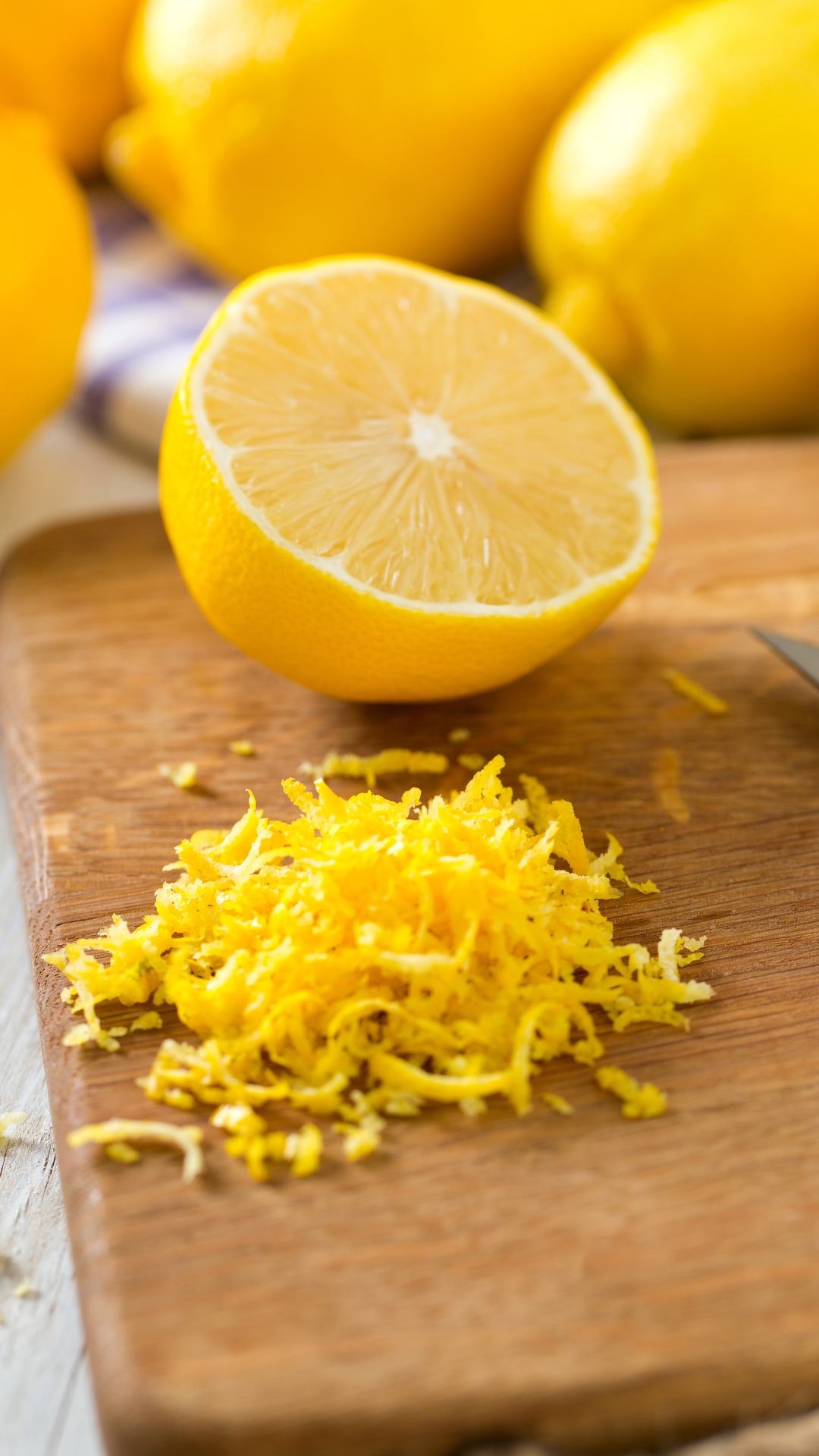 half a lemon and lemon zest on a cutting board