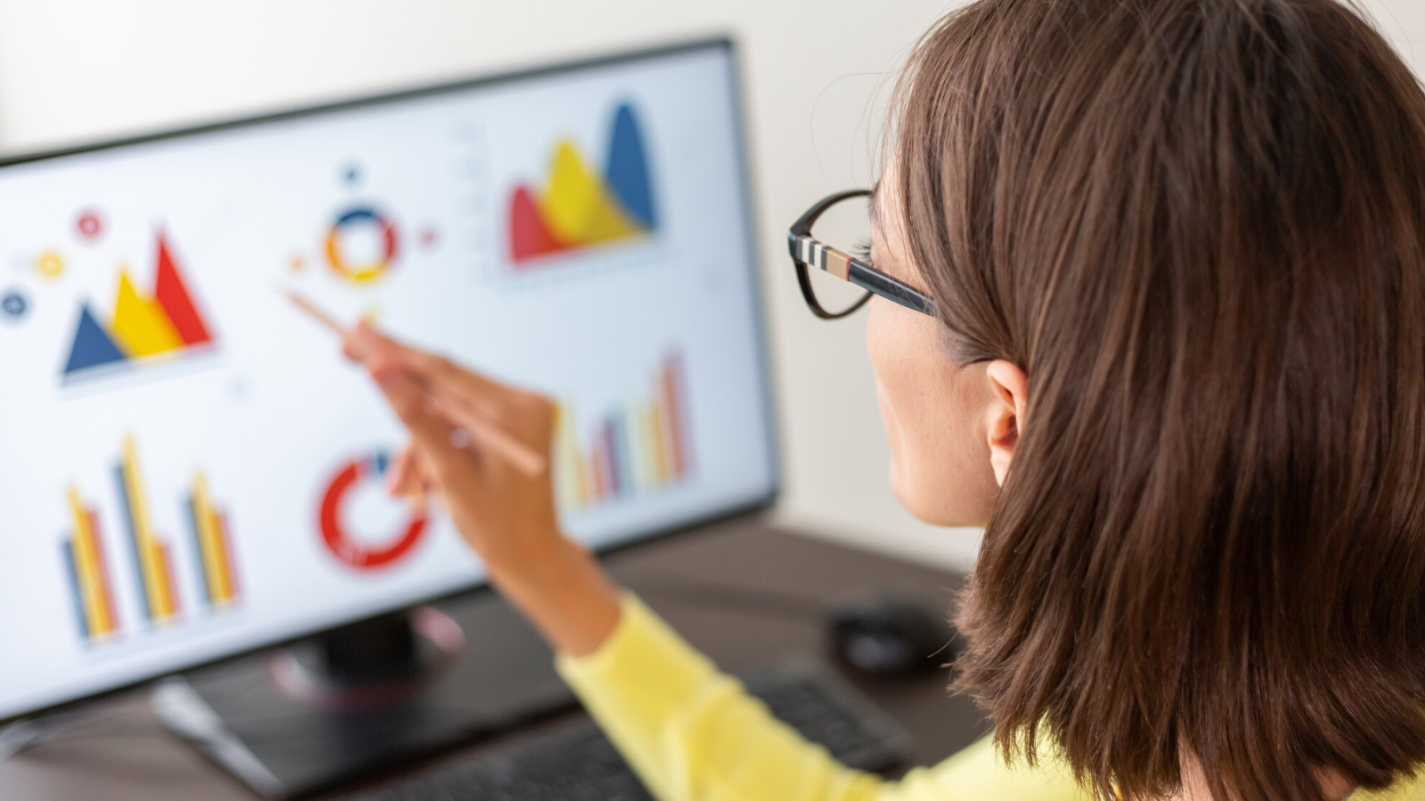 Woman analyzing graphs on a desktop screen, showing the marketing process of tracking and adjusting an SEO strategy.